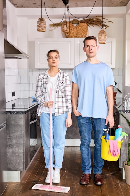 Portrait of confident caucasian janitors man and woman standing at home before housekeeping cleaning