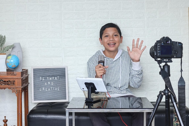 Portrait of confident and creative Asian child blogger talking on camera in a studio making video bl