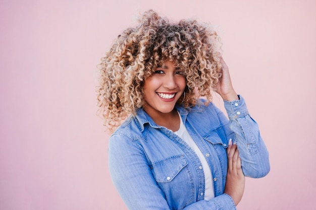 Portrait of confident curvy hispanic woman outdoors in spring pink wall body positivity