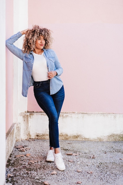 Photo portrait of confident curvy hispanic woman outdoors in spring pink wall body positivity