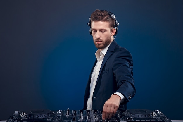 Portrait of confident DJ with stylish hair style and mixing table