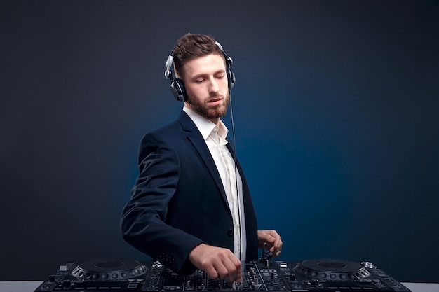 Portrait of confident DJ with stylish hair style and mixing table