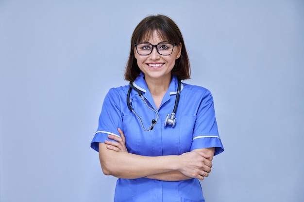 Portrait of confident female nurse with folded hands looking at camera