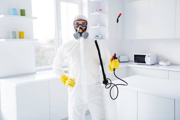 Portrait of confident guy in white safety protective uniform ready desinfect