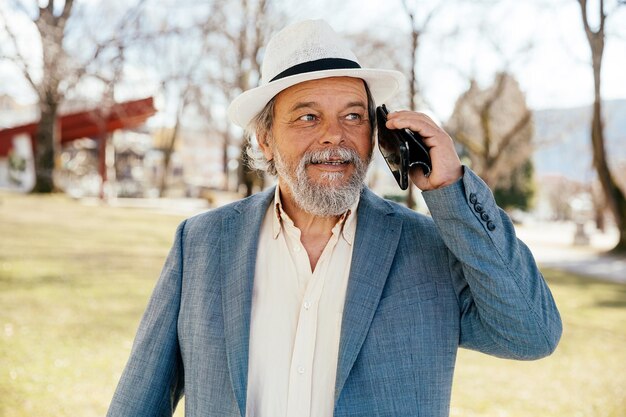 Portrait of a confident handsome mature man pensioner grandfather calling someone on the phone