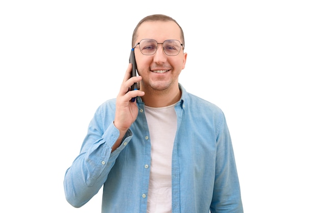 Portrait of a confident happy man with a phone in his hands looks at the camera on a white