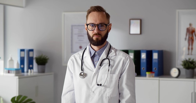 Photo portrait of confident male doctor with stethoscope around neck looking at camera