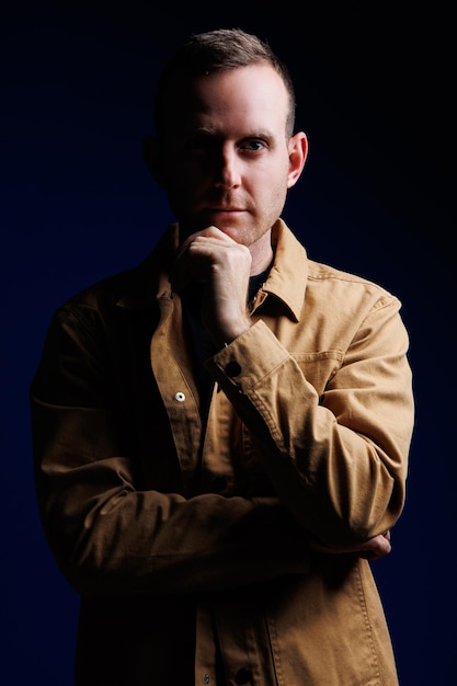 Portrait of a confident man on a dark background in a brown shirt The emotion of concentration A man without a smile