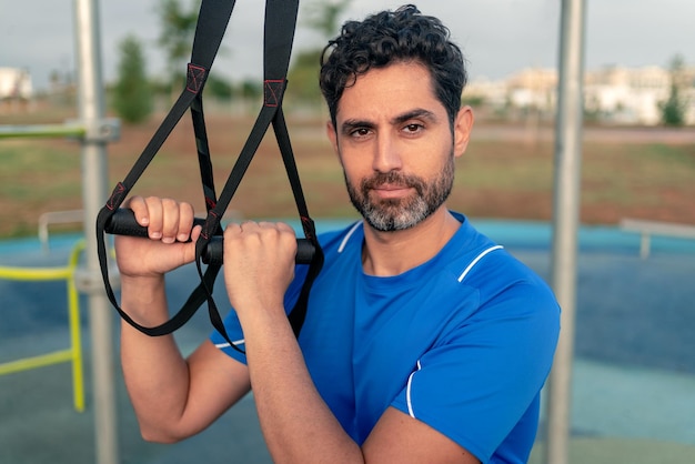 Portrait of confident man doing fitness exercises on a special hanging device