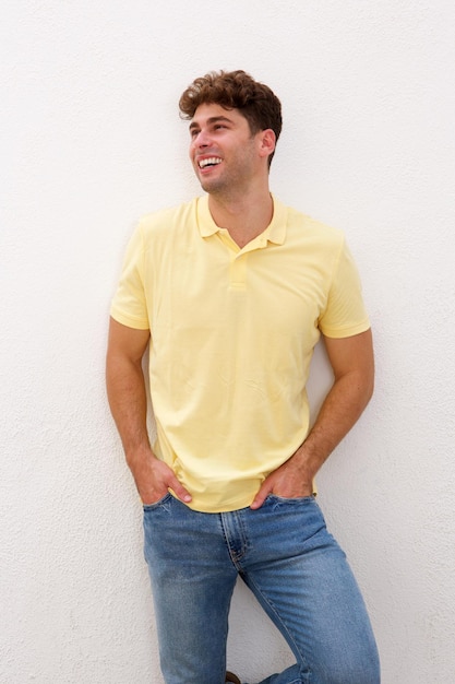 Portrait of confident man smiling and standing by white wall