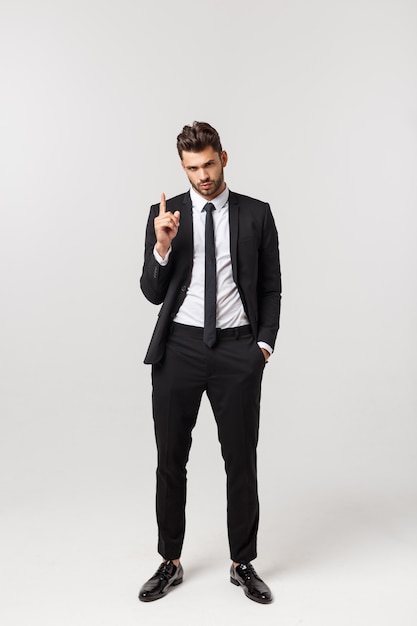 Portrait of confident mature businessman in formals standing isolated over white wall