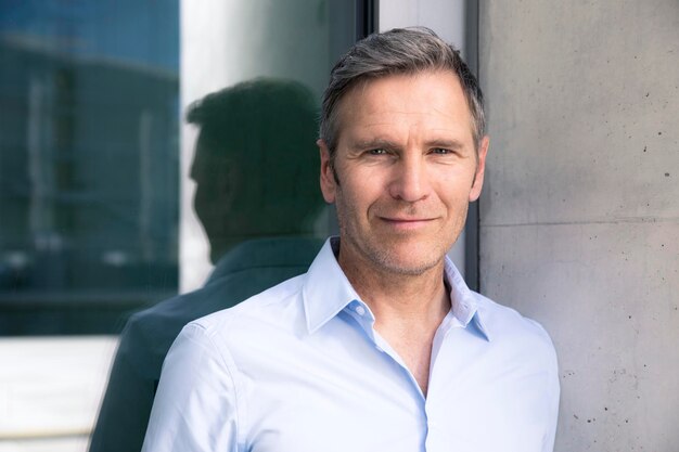 Portrait of confident mature businessman at a glass front