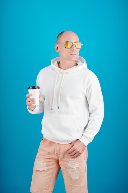 Portrait of confident mature man in sunglasses holding cup of take out coffee and looking away