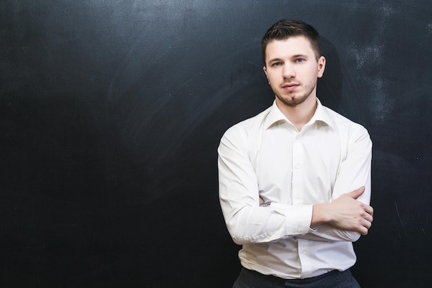 Portrait of confident office male with crossed arms isolated over black chalkboard