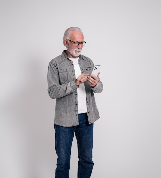 Portrait of confident old male executive messaging over mobile phone on isolated white background