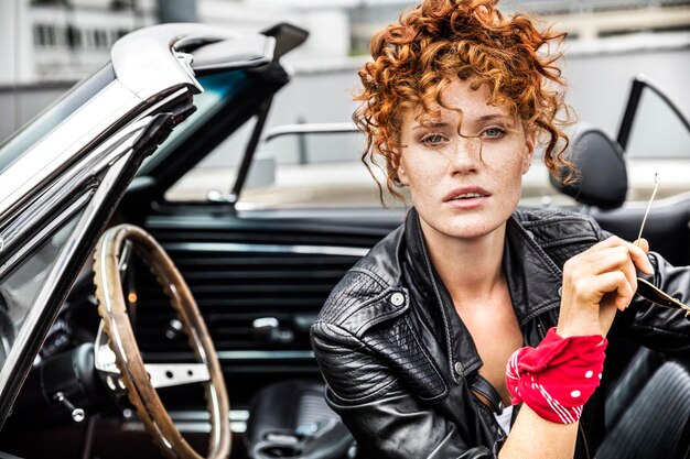 Portrait of confident redheaded woman in sports car