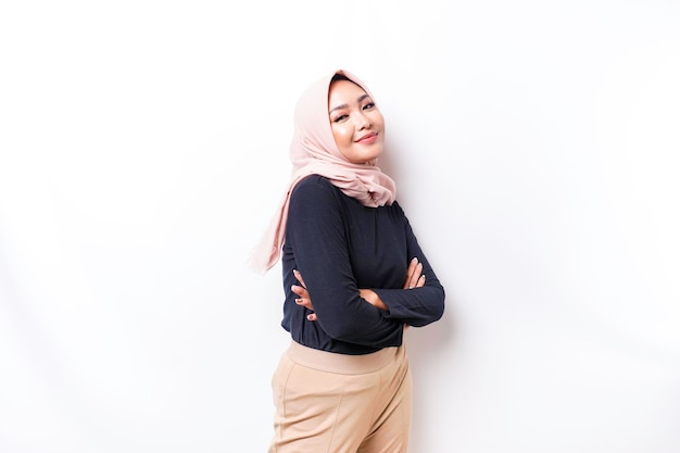 Portrait of a confident smiling Asian Muslim woman wearing hijab standing with arms folded and looking at the camera isolated over white background