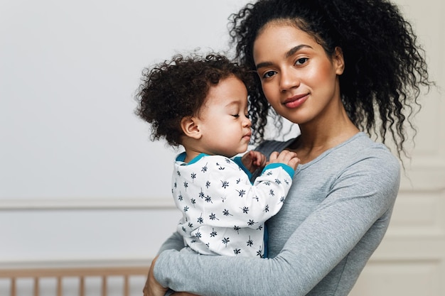 Photo portrait of confident smiling mother carrying baby boy at home