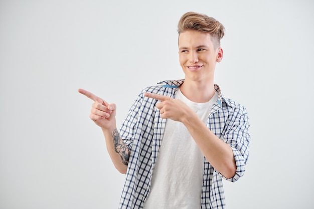 Portrait of confident smiling teenage boy winking and pointing sideways