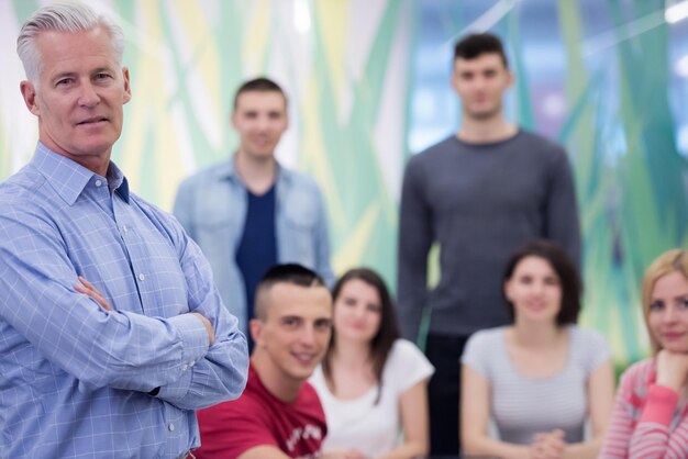 portrait of confident teacher,  students group in background