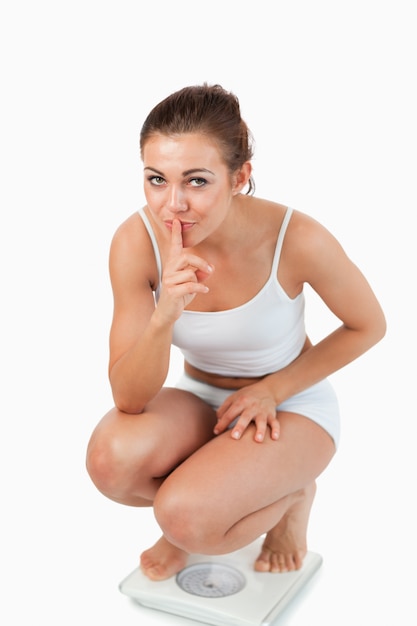 Portrait of a confident woman squatting on scales