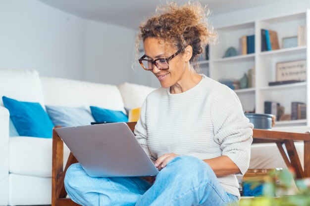 Portrait of confident woman writing on laptop at home sitting on the floor in indoor online leisure activity Social media and remote working business Modern female people using computer and smiling