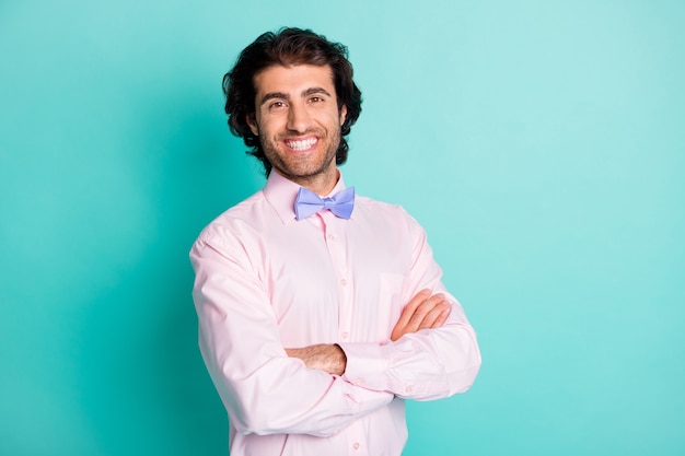 Portrait of confident young arabian man smiling friendly\
crossed his arms formalwear isolated teal color background