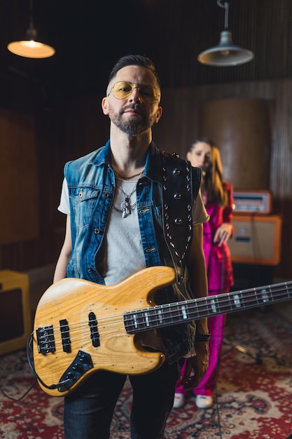 Portrait of an confident young bass guitar player in a recording studio