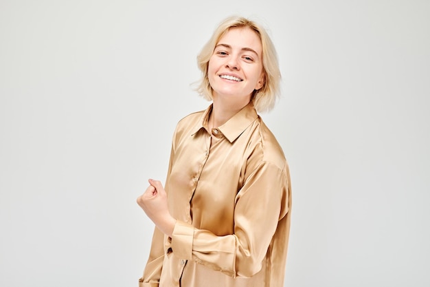 Portrait of confident young blonde woman showing biceps demonstrating strength isolated on white studio background Lucky winner concept