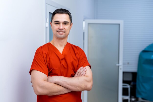 Portrait of confident young male doctor standing arms crossed at clinic Medical and health care concept