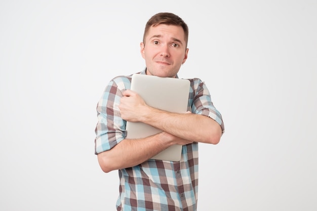 Portrait of confident young man laptop standing against blue wall