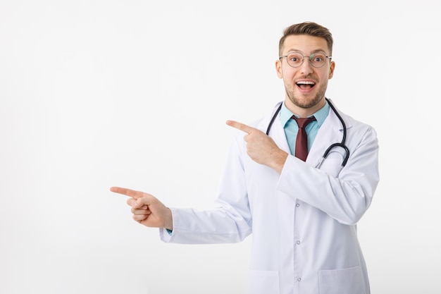 Photo portrait of confident young medical doctor on white background points to copy space