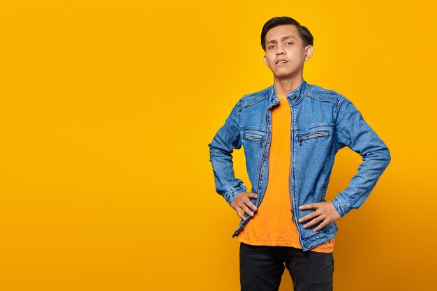 Portrait of confused asian man looking ahead on yellow background