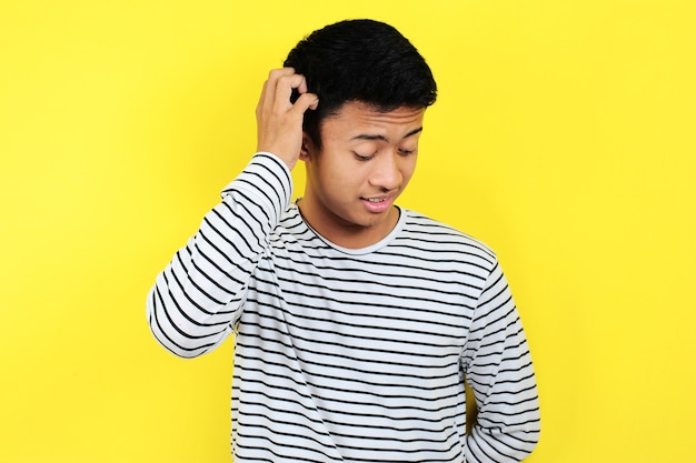 Portrait of confused man, isolated on yellow background