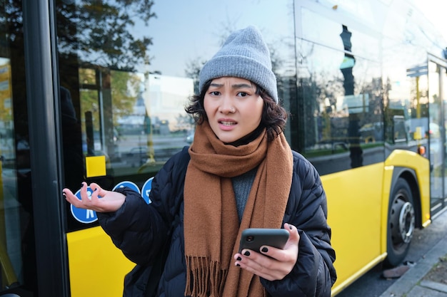 Portrait of confused young woman looking at her smartphone app with shocked and disappointed face           person