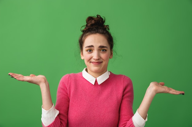 Portrait of a confused young woman standing isolated over green