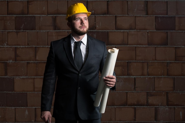 Portrait Of Construction Master With Yellow Helmet And Blueprint In Hands