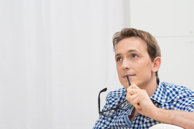 Portrait Of Contemplating Young Man Holding Eyeglasses