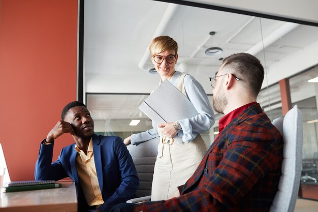 Portrait of contemporary multi-ethnic business team discussing work project in office focus on smiling female manager talking to colleagues, copy space