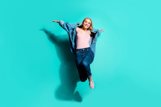 Portrait of cool cheerful girl jumping and posing isolated on blue