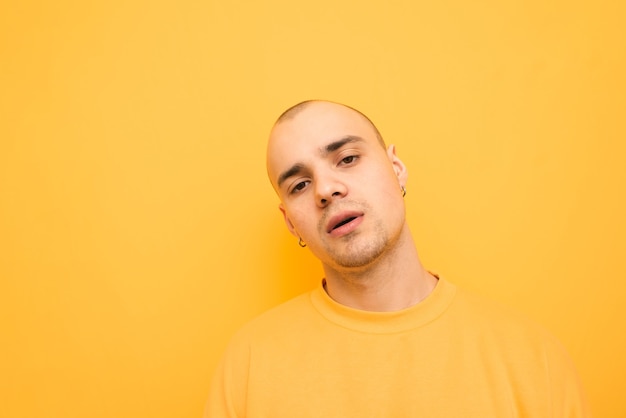 Portrait of a cool stylish young man in a yellow sweatshirt on a yellow