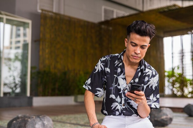 Portrait of cool young man outdoors during summer using phone