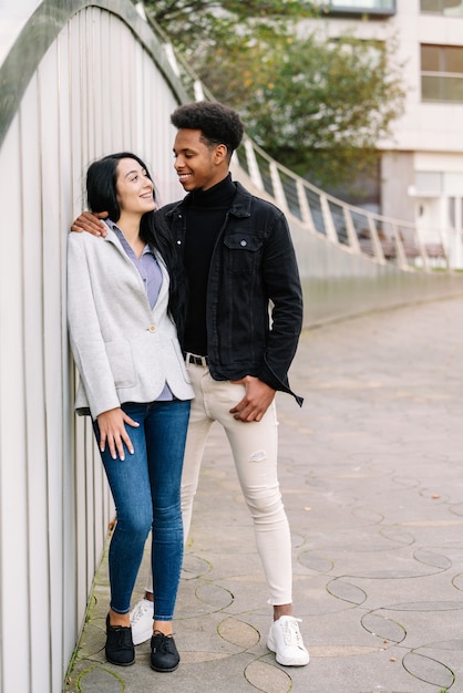 Portrait of a couple of a Caucasian girl and a Moroccan boy with very happy afro hair hugging with complicity on a visit to bilbao on their honeymoon