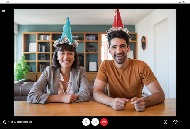 Foto ritratto di una coppia che festeggia il compleanno in una videochiamata da casa.