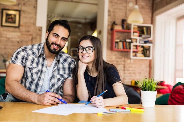 Ritratto di coppia di liberi professionisti uomo barbuto e ragazza bruna che lavorano con il computer portatile in un moderno ed elegante concetto di successo del lavoro di squadra dell'ufficio di coworking