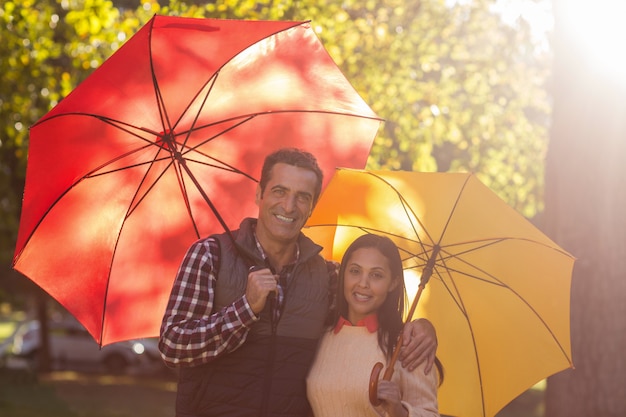 Portrait of couple holding umbrellas