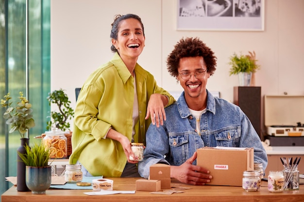 Portrait Of Couple Running Online Business From Home Packing Boutique Candles Ready For Shipping