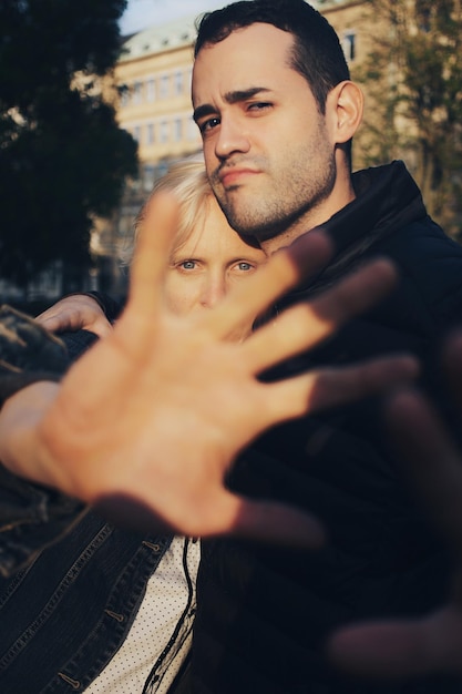 Photo portrait of couple showing stop gesture against trees