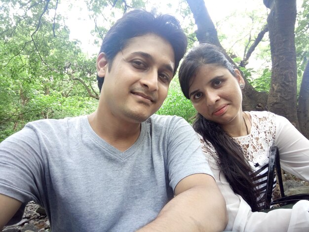 Portrait of couple standing against trees at forest