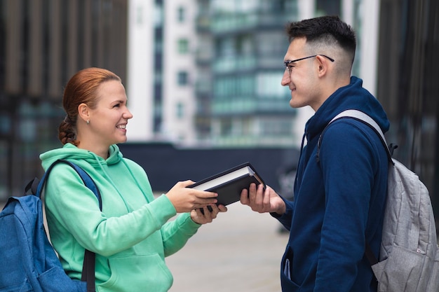 Portrait of couple of two beautiful happy university students outdoors in campus